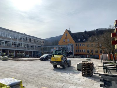 Baustelle mit einem gelben Radlader auf neu verlegten Pflastersteinen vor mehrer