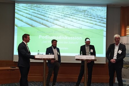 Vier Männer bei einer Podiumsdiskussion über die Zukunft des Betonbaus vor einer