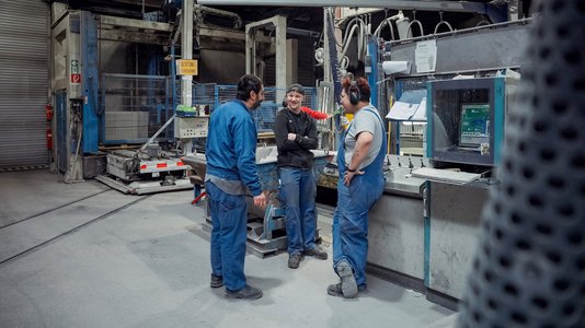 Vier Auszubildende in Blauarbeitsschutz unterhalten sich in einer industriellen 