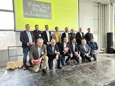 Gruppenfoto von Teilnehmern einer Branchenveranstaltung vor einer Präsentationsf